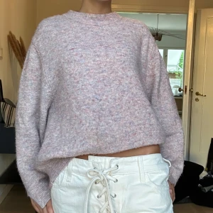 Ljuslila stickad tröja med loose fit - Supermjuk och fluffig stickad tröja i ljuslila med inslag av rosa och blått. Tröjan har en avslappnad, loose passform och långa ärmar. Perfekt för lager-på-lager och chill dagar.