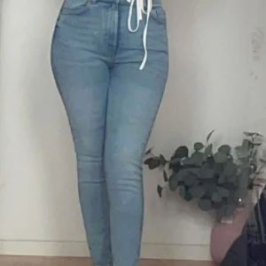 Ljusblå skinny jeans hög midja - Säljer ett par ljusblå skinny jeans med hög midja. Jeansen har klassisk femficksdesign, smal passform hela vägen ner och är tillverkade i mjukt denimtyg. Perfekta för dig som gillar en tight och modern look.