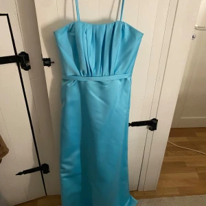Ljusblå balklänning från Forever Yours - Superfin ljusblå långklänning från Forever Yours med smala axelband och veckad överdel. Axelbanden går att ta av för att få en bandeu klänning. Perfekt för bal eller student!                              Plastskyddet medföljer om man vill!!!