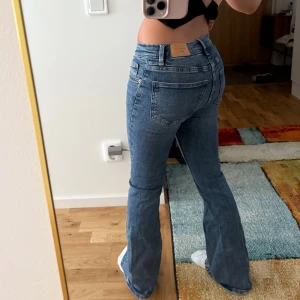 Gina tricot blå bootcut jeans - Säljer jeans i blå denim med bootcut från Gina tricot. Jeansen har normal passform, fem fickor och snyggt utställda ben. Det är slitage på ena benen där nere (se sista bild). Annars perfekta jeans för komfort och enkel look! 💞