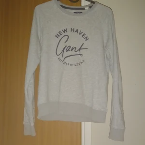 Ljusgrå sweatshirt från Gant - Ljusgrå sweatshirt från Gant med tryck 'New Haven Gant' i mörkblått framtill. 