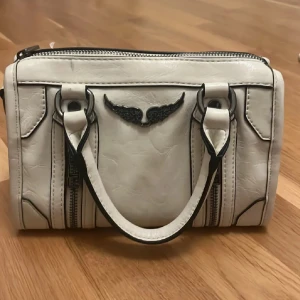 Zadig Voltaire väska - Snygg krämvit zadigväska! Inuti finns två mindre fack varav en av de har dragkedja och en stor yta. (Pris går att diskutera). Hör av er vid eventuella frågor💞