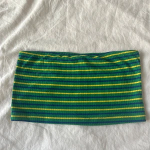 Gul grön blå randig tubtopp - En färgglad och fin tubtopp som är ribbad och har smala ränder i grönt, blått och gult. Materialet är stretchigt och sitter tight mot kroppen. Köpt från shein och kommer inte mer till användning. Kontakta gärna innan köp!