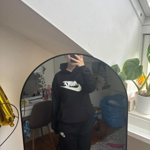 Svart Nike hoodie och Nike byxor SET - Svart hoodie från Nike med stor vit logga framtill. Använt bara hemma några gånger. Mjuk insida, passar till allt. Skriv för frågor eller fler bilder