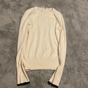 Beige långärmad tröja från Zara - Snygg beige långärmad tröja från Zara med svarta detaljer vid ärmsluten. Tröjan är enkel att matcha med olika outfits.