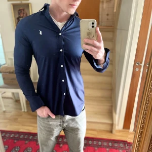 Marinblå Ralph Lauren skjorta - Säljer nu den här sjukt snygga skjortan från Ralph Lauren i storlek S. Som man kan se är den alldeles för liten på mig. Skjortan är så gott som ny! 