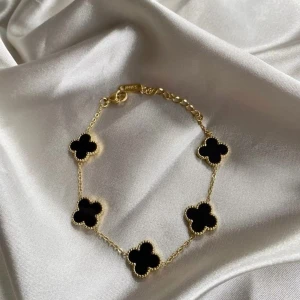 Van cleef Guldarmband  - Snyggt armband i guld med sex svarta fyrklöverformade hängen. Kedjan är tunn och elegant, perfekt för att ge en lyxig touch till din stil. Lås med justerbar längd för bästa passform. Den har använts ett fåtal gånger men är som ny