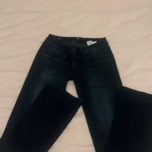 Svarta Low waist jeans från LTB - Säljer ett par svarta jeansbyxor från LTB med klassisk femficksdesign och bälteshällor. Jeansen har en Bootcut för en snygg look. Perfekta till vardags och enkla att matcha med olika toppar. W25 L32
