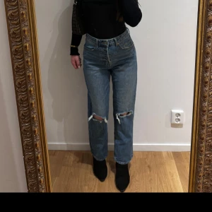Mörkblå högmidjade jeans med hål på knäna - Mörkblå jeans med hög midja och raka ben från H&M. Jeansen har slitna hål på båda knäna. 