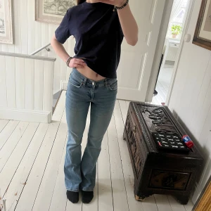 Blå bootcut jeans från Gina Tricot - Blå bootcut jeans från Gina Tricot. De är utsvängda och har en fin blå färg. De har använts väl men har fortfarande mycket kvar att ge. De är lite uttöjda och har lite slitningar längst ner på byxbenen (se näst sista och sista bilden).
