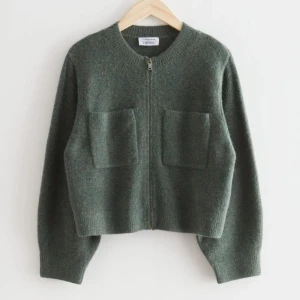 Mörkgrön stickad kofta med dragkedja - Säljer en mörkgrön stickad kofta från &stories med dragkedja framtill och två stora fickor på bröstet. Koftan har lång ärm och är croppad i modellen. Perfekt för lager-på-lager och enkel att matcha med jeans eller kjol. Finns ej att köpa längre 