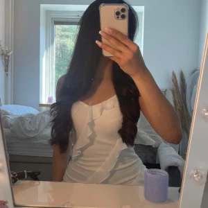 Vit volangklänning med omlottkänsla - Säljer en söt vit klänning med volangdetaljer och omlottkänsla. Klänningen har smala axelband och en figurnära passform som framhäver siluetten. Perfekt för sommarens alla tillfällen!(kontakta mig för fler bilder) 🥰