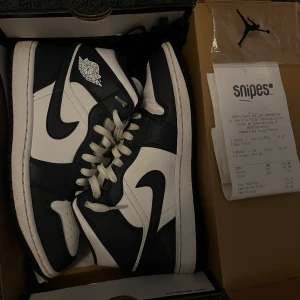 Nike Air Jordan 1 Mid Svart/Vit - Säljer ett par Nike Air Jordan 1 Mid White Metallic Gold Obsidian i storlek 42. Köpta på Snipes i Barcelona och medföljer kvitto, låda, och extra skosnören. Använda sparsamt och är i gott skick, ca 8,5/10. Nypris online ligger runt 2500kr. Hör av dig vid frågor 