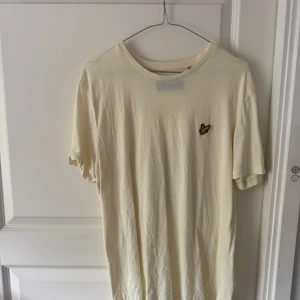 Vit t-shirt med broderad logga från Lyle & Scott -  en stilren vit t-shirt från Lyle & Scott med deras klassiska broderade gula fågel-logga på bröstet. Storlek L men passar M med.