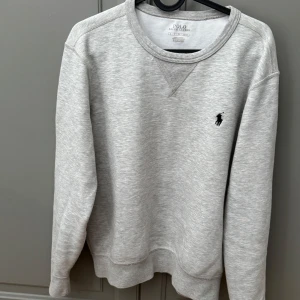 Ralph Lauren tröja - Säljer denna tröjan då den inte passar längre. Ljusgrå sweatshirt från Ralph lauren. Skick 7/10. Perfekt för en avslappnad och stilren look.