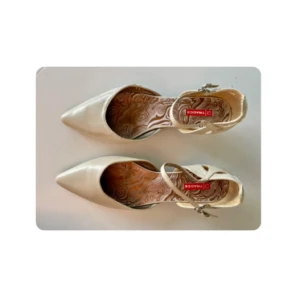 Vita kitten heals med axelrem - Snygga beige pumps från Tamaris med spetsig tå och smal klack. Skorna har en elegant ankelrem med spänne och ett mönstrat innerfoder. Perfekta för dig som vill ha en stilren och feminin look.