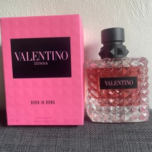 Valentino Donna Born In Roma Eau de Parfum - Exklusiv parfym från Valentino, Donna Born In Roma. Flaskan är fyrkantig med nitar i glaset och har en svart, matt kork. Parfymen har en rosa nyans och etiketten är svart med rosa text. Förpackningen är rosa med svart logga.
