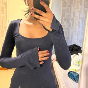 Mörkblå långärmad tröja  - Säljer en mörkblå långärmad tröja från Gina Tricot med rundad, djup urringning. Tröjan har en figurnära passform och är tillverkad i ett mjukt, stretchigt material. 