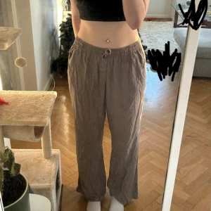 Bruna linnebyxor - Bruna linnebyxor med resår i midjan och snörning framtill. Byxorna har raka ben och sidfickor. Använd fåtal ggr