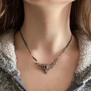 Halsband med ädelsten - Ett vackert unikt halsband i silver (295 märkning finns) med en röd granat i mitten. Designen är detaljerad med små dekorativa element och hematiter som ger en klassisk och tidlös känsla. Köptes secondhand som present men det blev ändrade planer. ✨