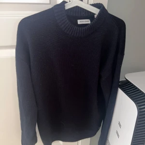 Svart stickad tröja från Jack & Jones - Säljer en stilren svart stickad tröja från Jack & Jones. Tröjan har en klassisk rund hals och långa ärmar, perfekt för kyligare dagar. Passar bra till både jeans och chinos.