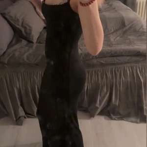 Svart långklänning - Elegant svart långklänning med en tight passform. Klänningen är ärmlös och har en stilren design som passar perfekt för festliga tillfällen.