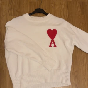 Ami paris vit tröja - Säljer en stilren vit tröja från Ami Alexandre Mattiussi med ett rött hjärta och bokstaven 'A' på bröstet. Tröjan har långa ärmar och ribbade kanter vid ärmslut och nederkant. Perfekt för en trendig och avslappnad look. Den är storlek S men passar även XS