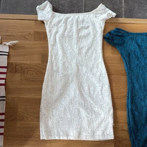 Vit spetsklänning - Säljer en elegant vit spetsklänning med offshoulder-design. Klänningen har en tight passform och är perfekt för sommarens festligheter. Den är kort och har ett vackert mönster i spets som ger en romantisk känsla. Perfekt för att känna sig extra fin!
