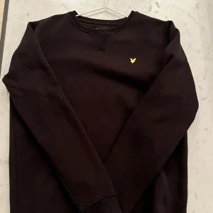 Svart tröja från Lyle & Scott - Säljer en stilren svart tröja från Lyle & Scott med deras ikoniska logga i gult på bröstet. Inga tecken på slitage!