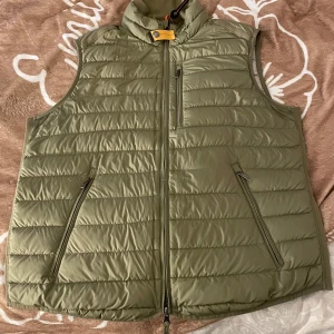 Grön dunväst - Snygg grön dunväst från Parajumpers med dragkedja framtill och praktiska fickor. Västen har en stilren design med hög krage och diskreta detaljer. 