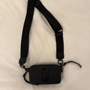Svart axelväska från Marc Jacobs - Snygg svart axelväska från Marc Jacobs med justerbar rem och logotypdetalj. Väskan kommer med en praktisk dustbag.