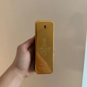  1 Million  100ml - Snygg och lyxig parfymflaska i guld från Paco Rabanne, formad som en guldtacka. Flaskan har en elegant design med märkets logotyp och namnet '1 Million' ingraverat på framsidan. Perfekt för den som vill ha en exklusiv doftupplevelse.halva kvar det finns en liten defekt på den men kontakta mig för mer information 
