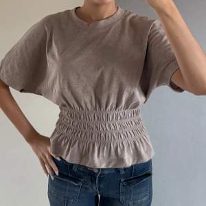Säljer en beige kortärmad topp med resår i midjan som ger en fin volangeffekt. Från hm❤️