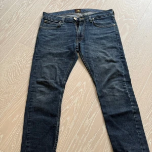 Blå jeans från Lee Luke Strl: 30/32 - Snygga blå jeans från Lee med klassisk femficksdesign och dragkedja. De har en normal passform och är perfekta för en avslappnad stil. Jeansen har en knapp med Lee-logga och är tillverkade i slitstarkt denim.