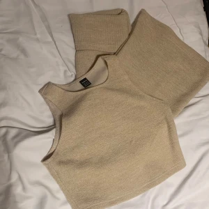 Beige matchande sett linne och fold over utsvängda byxor - Säljer en beige topp med rund halsringning och matchande utsvängda byxor som man viker ner vid midjan. Perfekt för en avslappnad och trendig look. 