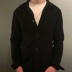 Overshirt från A Day's March - Snygg svart overshirt från A Day's March med knappar framtill och en bröstficka samt två midje-fickor | Storlek: S | Pris: 699kr | Nypris: 1700kr | Bra skick! | Vid intresse kontakta mig!