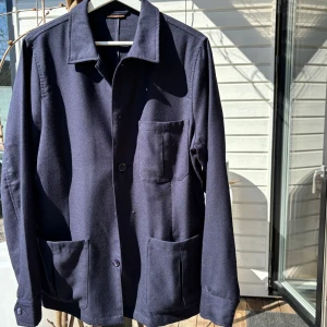 Stenströms overshier Ull - Säljer en stilren mörkblå jacka från Stenströms. Jackan har en klassisk design med knappar framtill och flera praktiska fickor. Perfekt för en elegant look. 100% Ull