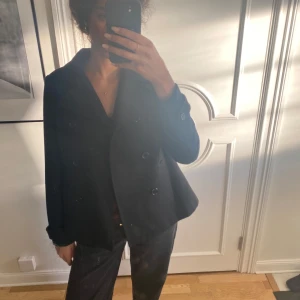 Svart kappa med knappar - Snygg svart kappa med dubbelknäppning och långa ärmar. Perfekt för höst och vår. Klassisk design som passar till många tillfällen.  Använt fåtal gånger, kontakta vid frågor 