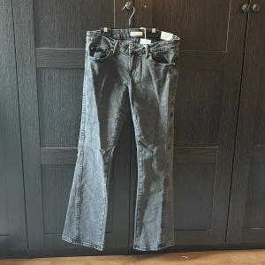 Grå low rise twisted bootcut jeans från Gina tricot  - Ett bara gråa low rise jeans från Gina tricot, aldrig använda. Storlek 38, twisted bootcut med fin design på baksidan.