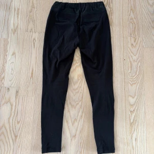 Svarta kostymbyxor från Kaffe - Svarta kostymbyxor från Kaffe med elastisk midja och smal passform. Byxorna har diskreta bakfickor och är tillverkade i ett mjukt material som känns bekvämt mot huden. Perfekta för en stilren och enkel look. Extremt sköna men ändå proffsiga. Passar 34-36. Nypris: 899 kr. Oanvända! Hör av dig för fler bilder och mått! 😊☀️ 🌱