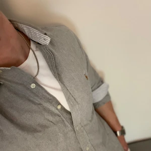Ljusgrå skjorta från Ralph Lauren - Säljer en ljusgrå skjorta från Ralph Lauren i slim fit-modell. Skjortan har klassisk krage, knappar framtill och en liten broderad logga på bröstet. Perfekt för dig som gillar stilrena och tidlösa plagg.