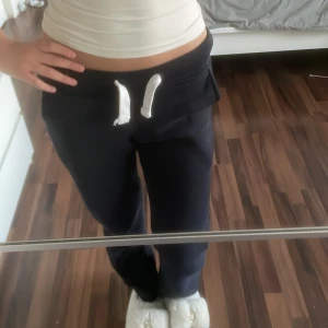 Mörkblå mjukisbyxor från Russemerch - Mörkblå mjukisbyxor från Russemerch med vita snören i midjan. Byxorna har en normal passform och är perfekta för en avslappnad stil. Tillverkade i mjukt material för extra komfort. De är i storlek XXS long edition.