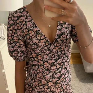 Blommig omlottklänning med volang - Säljer en söt kort blommig omlottklänning💐Perfekt för vår och sommar!🥰