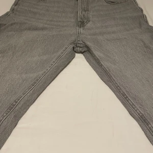 Grå jeans från Jack & Jones Loose/Chris - Säljer ett par grå jeans från Jack & Jones i modellen Loose/Chris. Byxorna har en lös passform och klassisk femficksdesign. Perfekta för dig som gillar en avslappnad stil. Stängs med dragkedja och knapp. Skick 8/10, storlek 29,30