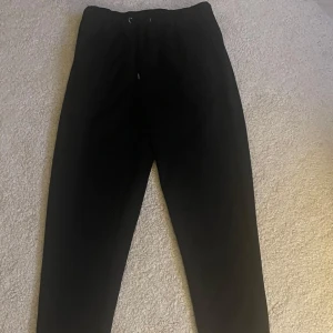 Svarta mjukisbyxor - Svarta mjukisbyxor med elastisk midja och dragsko. Byxorna har en rak passform och är perfekta för en avslappnad stil. Mjukt material som känns skönt mot huden.