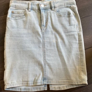 Ljusblå jeanskjol från Cubus - Ljusblå jeanskjol från Cubus i klassisk femficksmodell med knapp och dragkedja framtill. Kjolen har en liten slits bak och bälteshällor i midjan. Perfekt till vardags för en avslappnad look.