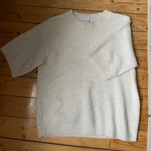 Krämvit stickad kortärmad tröja - Säljer en mjuk och enkel beige stickad tröja med korta ärmar och rund halsringning.  St 170 barnstorlek men är ganska stor i storleken och passar XS och S. Lite nopprig nedtill på framsidan 