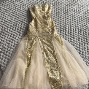 Champagnefärgad bal/fest paljettklänning med tyll - Säljer en glittrig, axelbandslös långklänning i champagnefärg med paljetter och tyllkjol. Klänningen har en figurnära passform upptill och vida tyllpaneler nedtill för en dramatisk look. Perfekt för bal eller fest! 💫