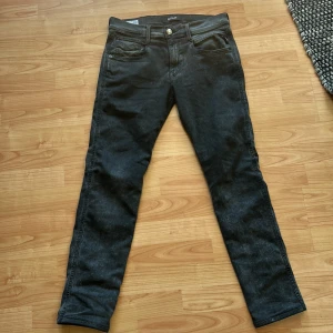 Gråa hyperflex jeansbyxor från Replay - Säljer ett par svarta Replay hyperflex jeansbyxor i klassisk femficksmodell. Byxorna har raka ben, normal passform och stängs med dragkedja och knapp. Perfekta för dig som gillar stilrena och tidlösa jeans. Jeansen är L32 men är dock uppsydda ca 1cm som man kan se på bild fyra.