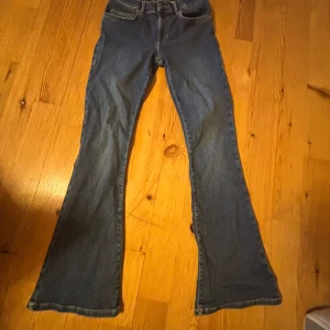 Blå low flare jeans med utsvängda ben - Säljer ett par blå jeans med låg midja och utsvängda ben, modell low flare. Klassisk femficksdesign och längd 31. stretchigt jeans matriall Perfekta för dig som gillar retrostil och vill ha ett par jeans med lite extra attityd.
